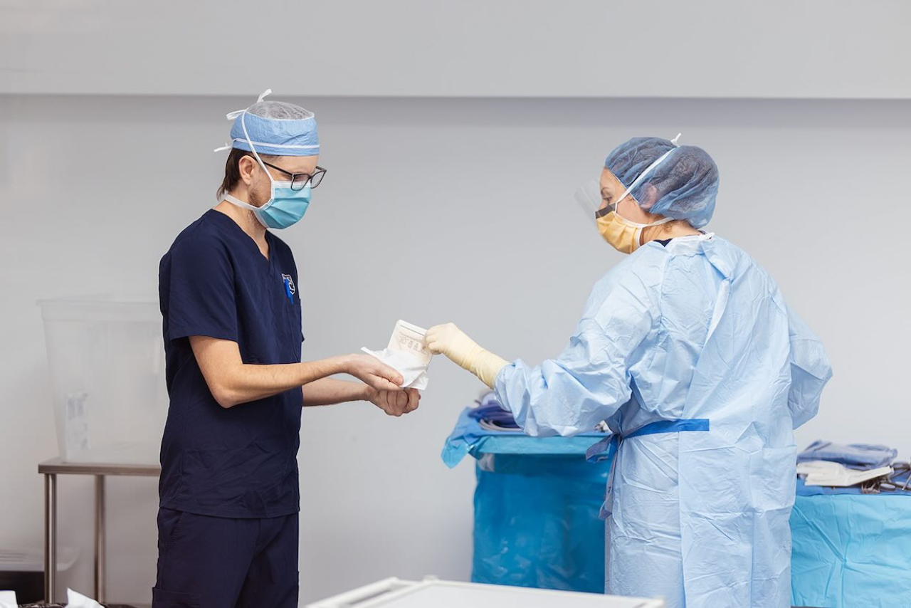 assistant handing sterile product to doctor.