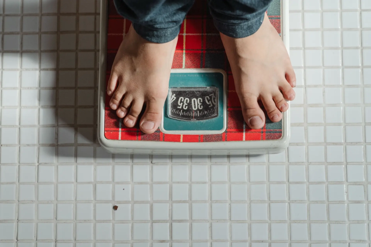 A person standing on a red plaid scale with bare feet.