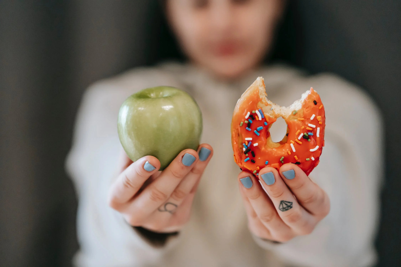 Healthy eating and healthy diet choices, person holding a donut and an apple.