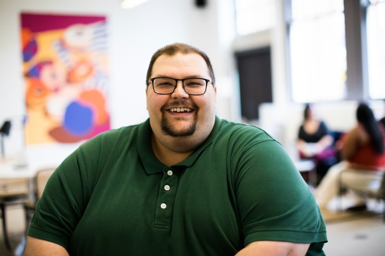 Smiling man seated in a bright communal space.