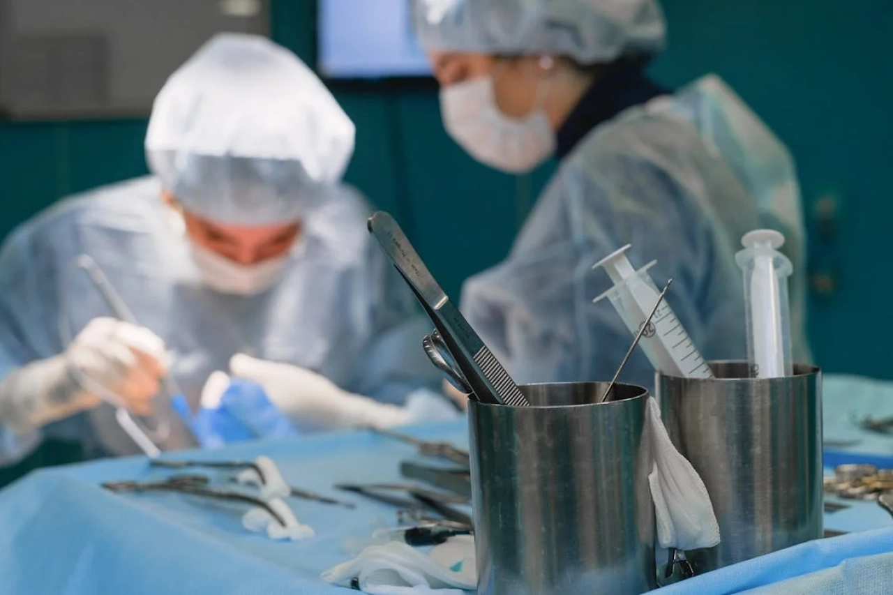 surgeons operating on patient in background, surgical instruments in foreground.