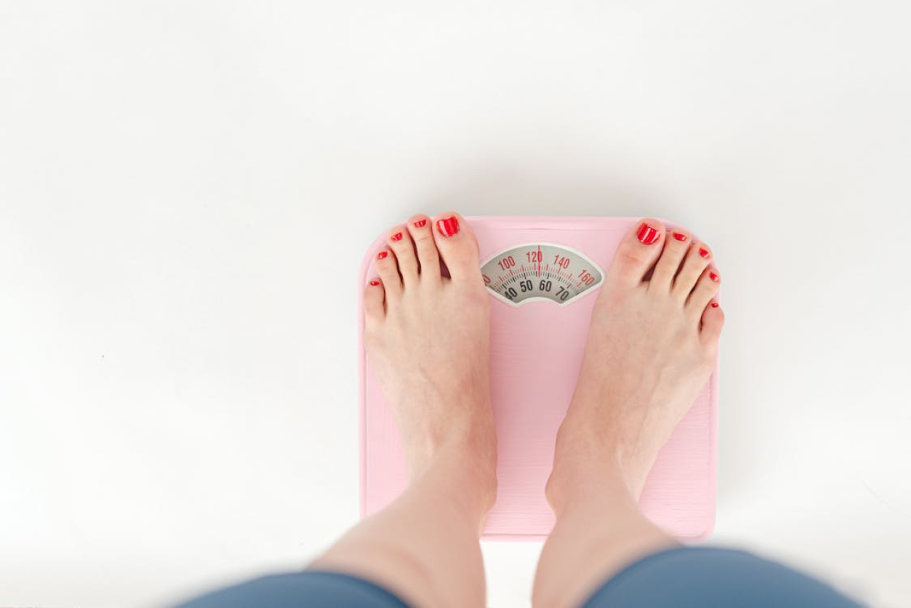 woman weighing herself on a balance scale.